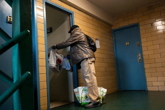 Victor Coles delivers a meal from the food distribution by the organization Urban Upbound, to an elderly woman at the Queensbridge Housing complex on April 16th, 2020.